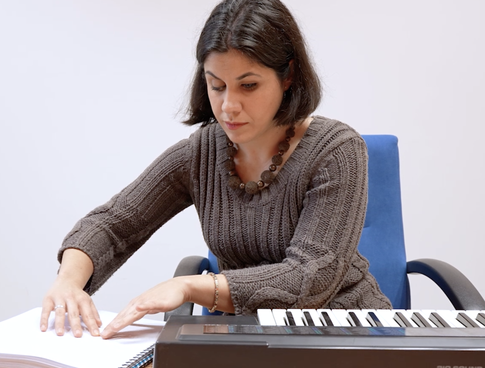 Marina tocando el piano y leyendo una partitura en braille