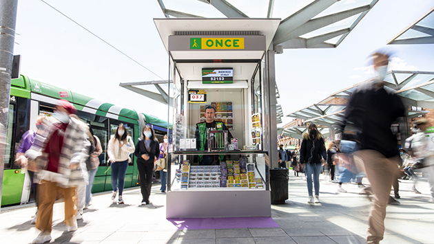 Vendedor de la ONCE en su quiosco ubicado en una estación de tren por la que transita mucha gente