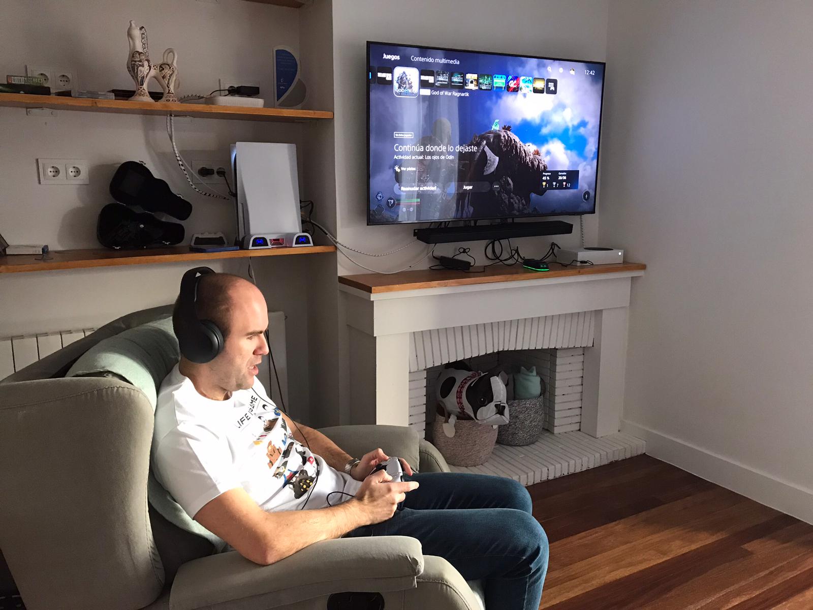 Sergio Vera a la derecha, sentando con un mando en las manos, jugando a la videoconsola sin mirar la pantalla