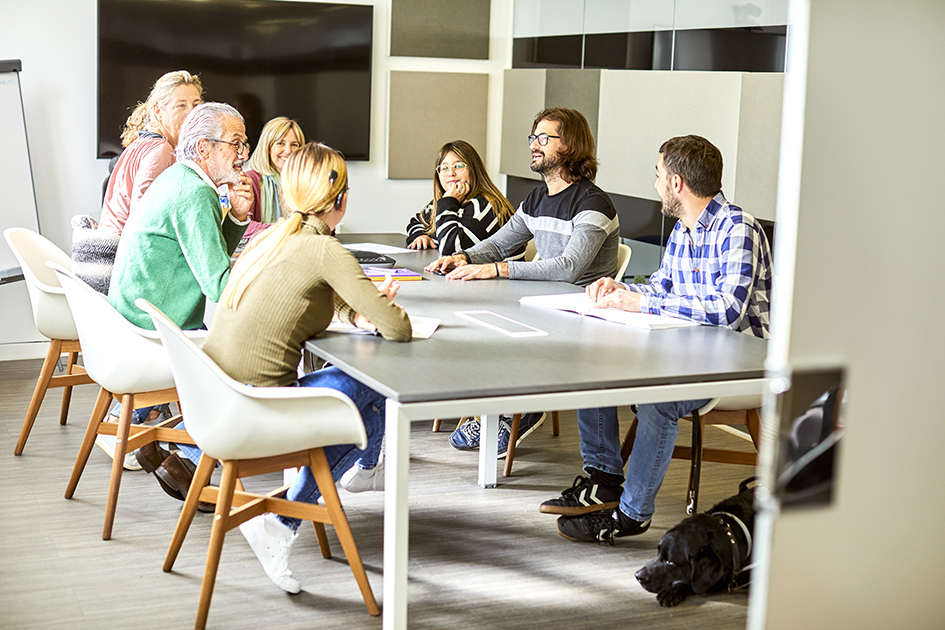 Un grupo de personas con y sin discapacidad reunidas alrededor de una mesa