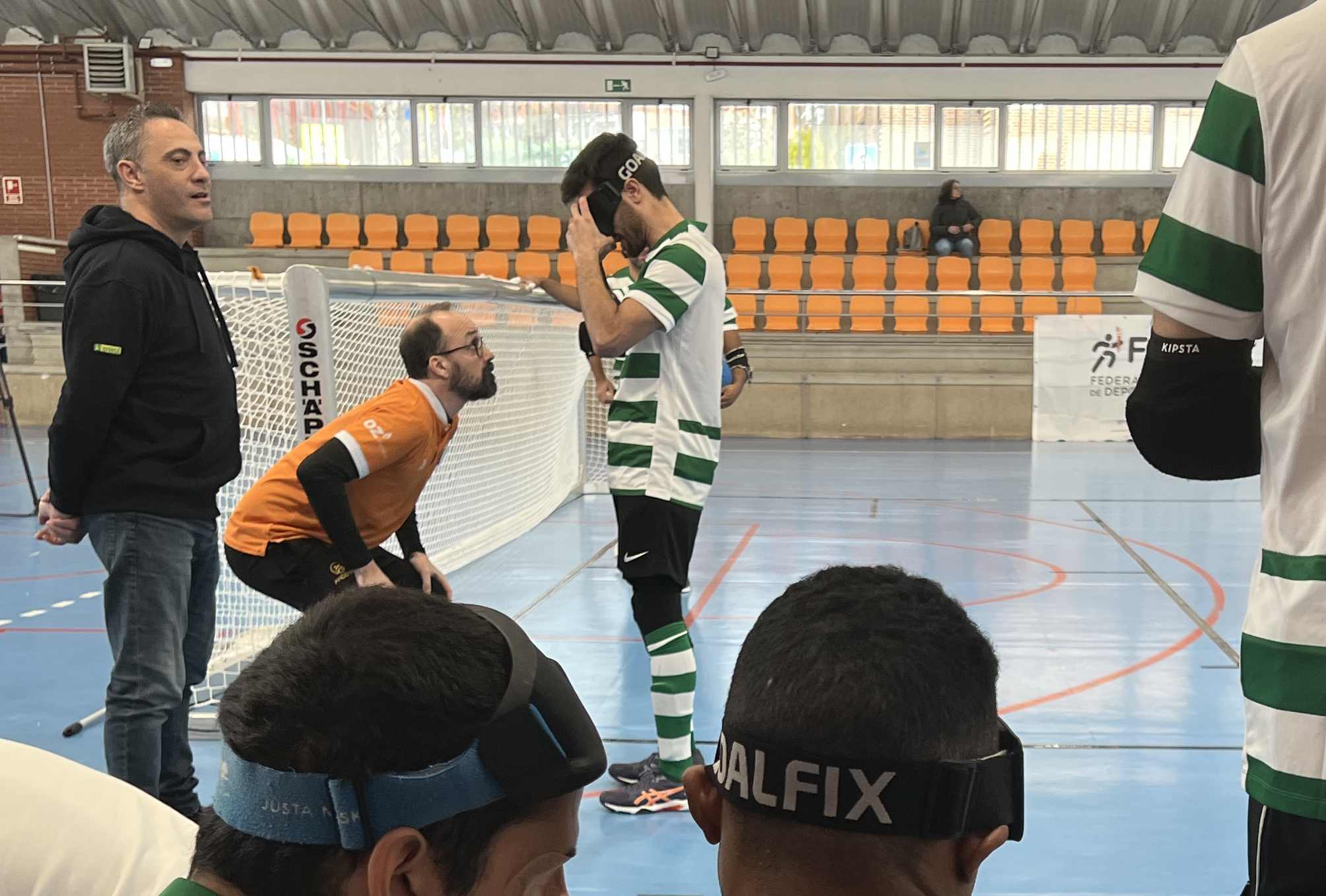 Un árbitro de goalball revisando el antifaz de un jugador antes de salir al campo