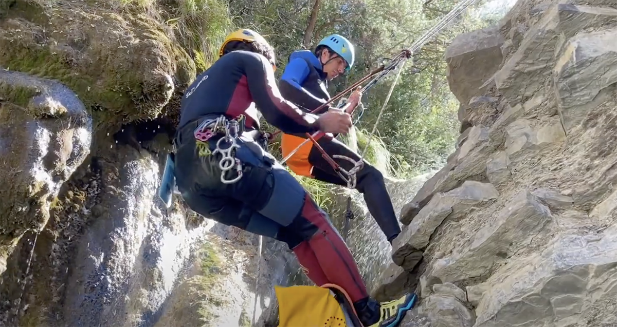 Uno de los miembros del equipo bajando por una cascada con la ayuda de un guía