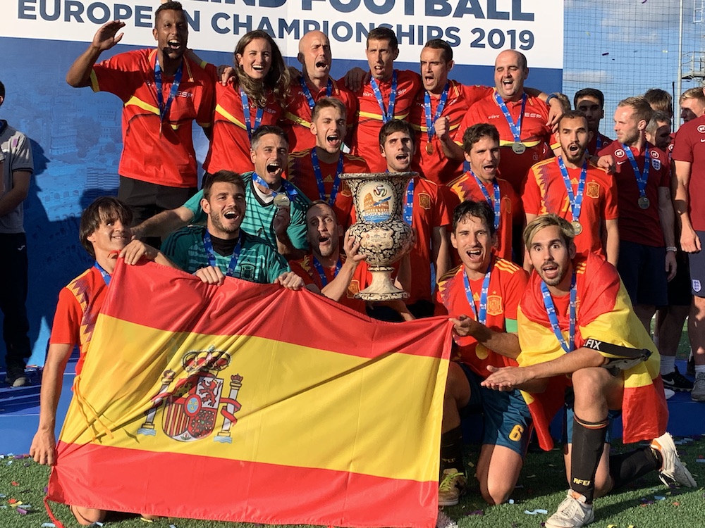 La Selección Española con la Copa de Campeones y celebrando su victoria ante una bandera de España.